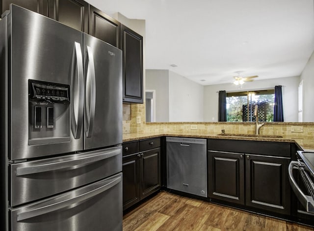 kitchen with light stone counters, sink, backsplash, and appliances with stainless steel finishes