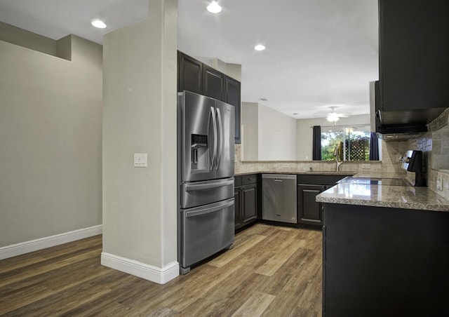 kitchen with dark hardwood / wood-style flooring, appliances with stainless steel finishes, backsplash, and light stone counters