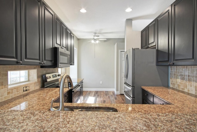 kitchen with sink, ceiling fan, stainless steel appliances, light stone countertops, and decorative backsplash