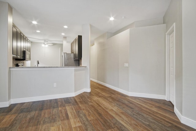 kitchen featuring sink, stainless steel fridge, ceiling fan, kitchen peninsula, and dark wood-type flooring