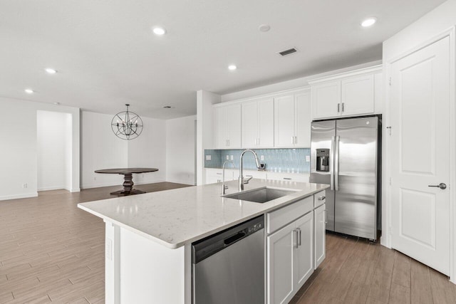 kitchen with white cabinetry, appliances with stainless steel finishes, sink, and an island with sink