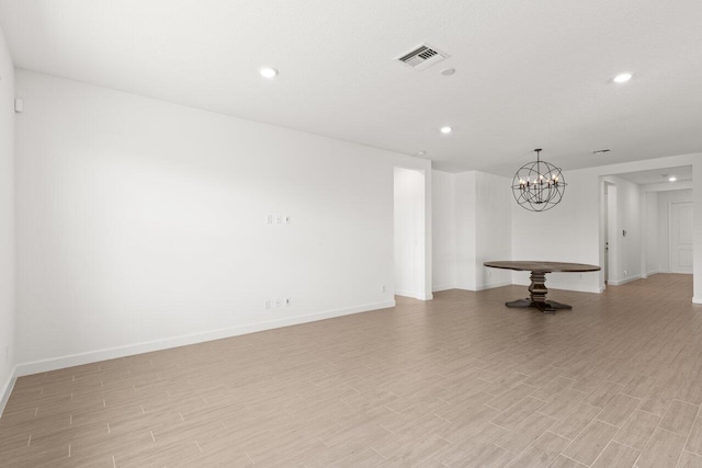 spare room with a chandelier and light hardwood / wood-style floors