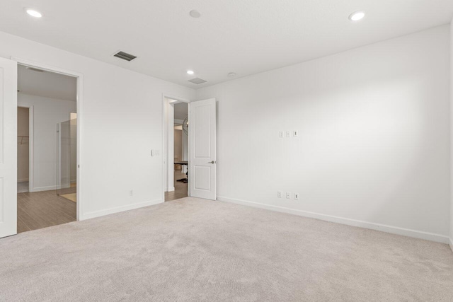 unfurnished bedroom with a walk in closet and light carpet