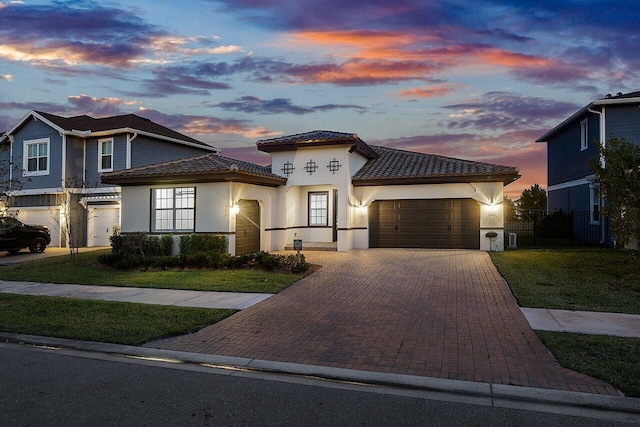 mediterranean / spanish-style home featuring a yard and a garage