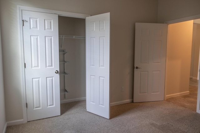 unfurnished bedroom featuring light colored carpet and a closet