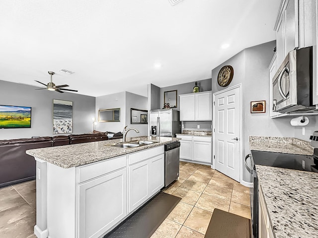 kitchen featuring appliances with stainless steel finishes, sink, light stone countertops, and a kitchen island with sink