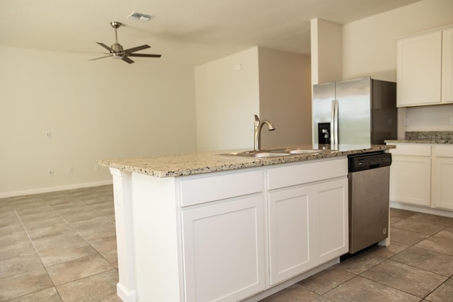 kitchen featuring sink, stainless steel appliances, light stone counters, white cabinets, and a center island with sink