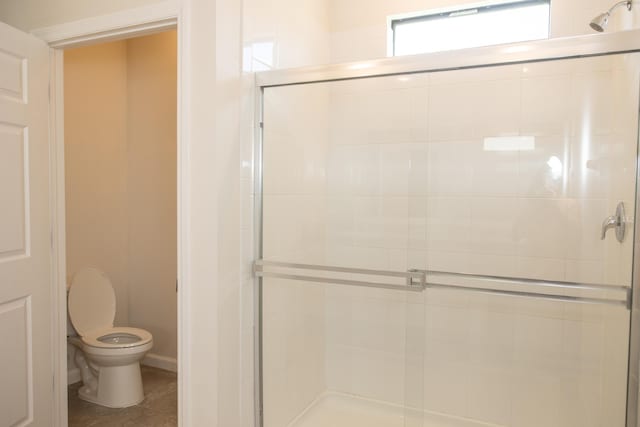 bathroom with a shower with door, tile patterned flooring, and toilet