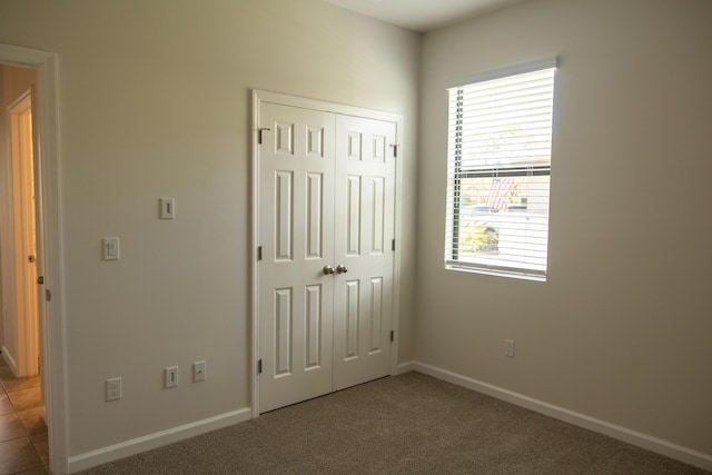 unfurnished bedroom featuring dark carpet and a closet