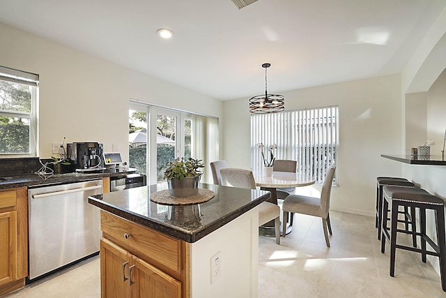 kitchen with decorative light fixtures, plenty of natural light, stainless steel dishwasher, and a center island