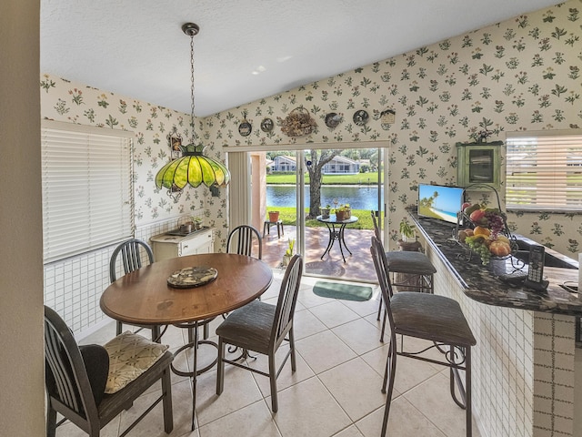 dining area with vaulted ceiling, light tile patterned floors, and a textured ceiling