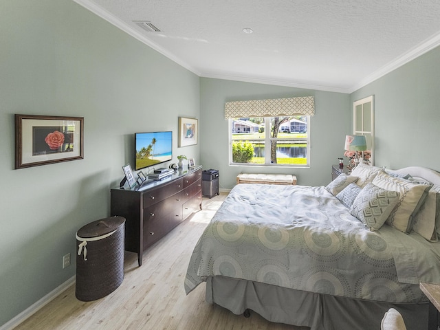 bedroom with crown molding, lofted ceiling, and light wood-type flooring