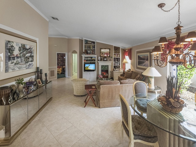 living room featuring light tile patterned floors, crown molding, built in features, a premium fireplace, and a chandelier