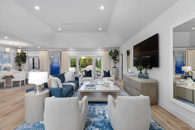 living room featuring a notable chandelier, light hardwood / wood-style floors, and a raised ceiling