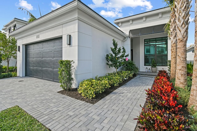 exterior space with a garage, decorative driveway, and stucco siding