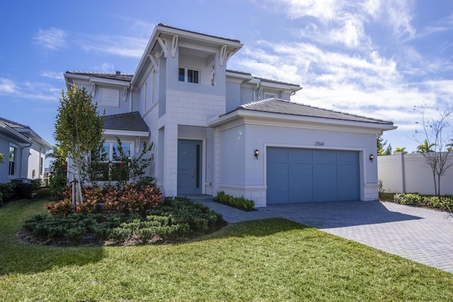 view of front of property with a front lawn, a tile roof, decorative driveway, fence, and an attached garage