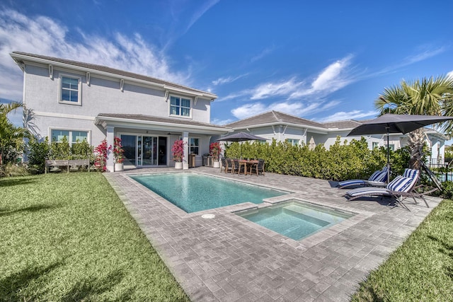 rear view of property with a yard, a patio area, a pool with connected hot tub, and stucco siding