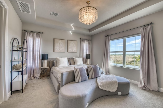 carpeted bedroom with a tray ceiling and an inviting chandelier