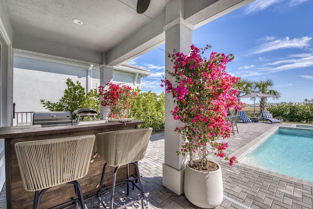 exterior space featuring ceiling fan, exterior bar, a patio, and area for grilling