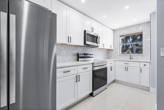 kitchen featuring light tile patterned floors, decorative backsplash, stainless steel appliances, and white cabinets