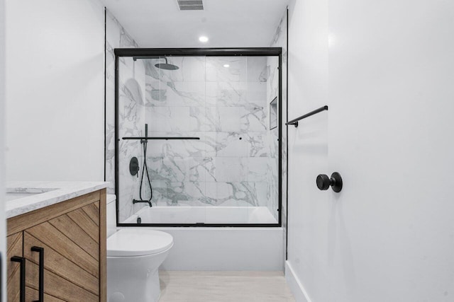 full bathroom featuring enclosed tub / shower combo, vanity, and toilet