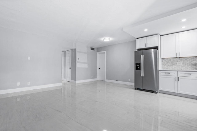 kitchen featuring white cabinetry, stainless steel fridge, and backsplash