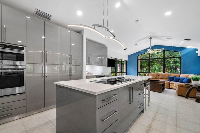 kitchen with gray cabinets, sink, hanging light fixtures, a center island, and black electric stovetop