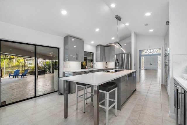 kitchen featuring stainless steel refrigerator with ice dispenser, a breakfast bar area, gray cabinetry, and decorative light fixtures