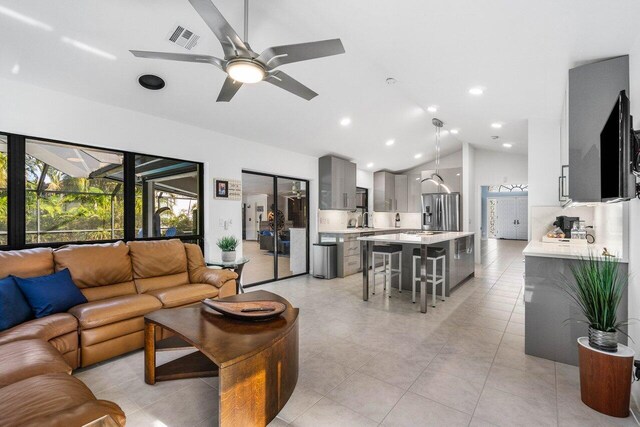 tiled living room featuring ceiling fan and vaulted ceiling