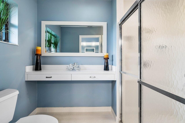 bathroom featuring a shower with shower door and toilet