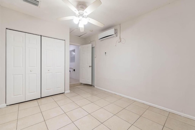 unfurnished bedroom featuring light tile patterned flooring, a closet, ceiling fan, and a wall unit AC