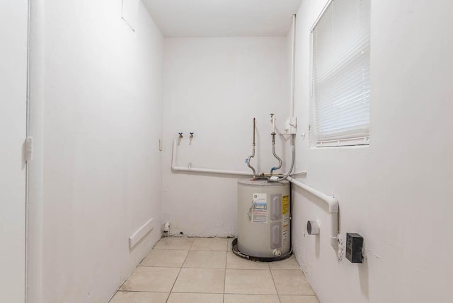 laundry area featuring water heater and light tile patterned floors