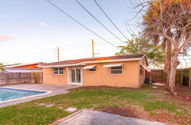 back of property with a yard, a fenced in pool, a patio area, and central air condition unit