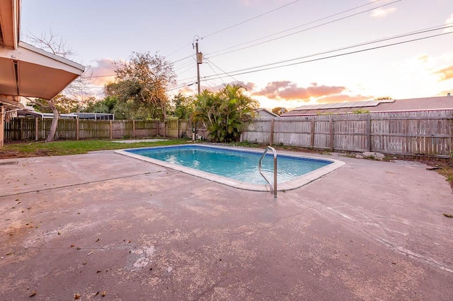 pool at dusk with a patio area