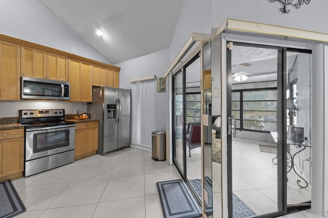 kitchen with stainless steel appliances, lofted ceiling, and light tile patterned floors