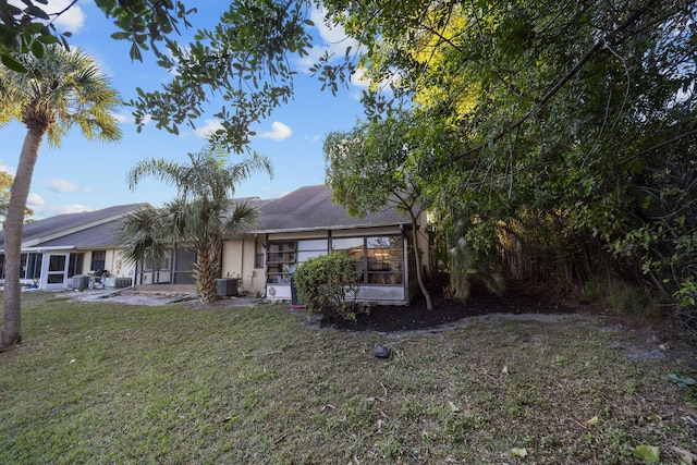 rear view of property with a sunroom, a lawn, and central air condition unit