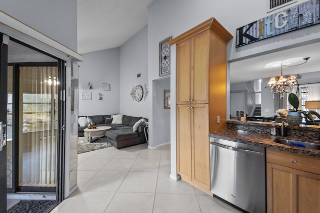 kitchen with sink, light tile patterned floors, dishwasher, a notable chandelier, and dark stone counters