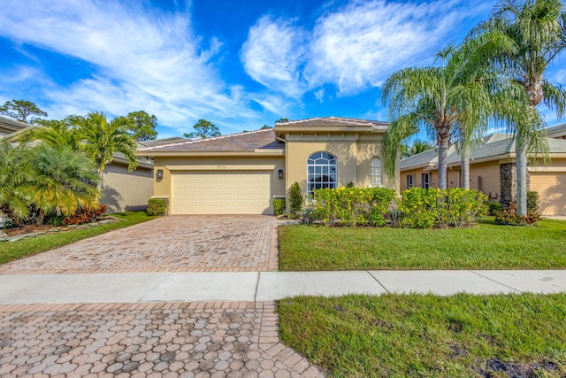 mediterranean / spanish-style home with decorative driveway, an attached garage, a front yard, and stucco siding