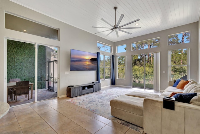 living area with light tile patterned floors, wood ceiling, baseboards, a ceiling fan, and crown molding