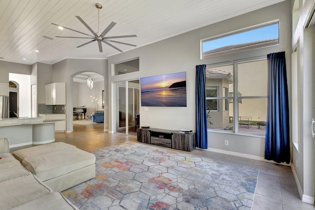 living room featuring arched walkways, light tile patterned flooring, ceiling fan with notable chandelier, wood ceiling, and baseboards