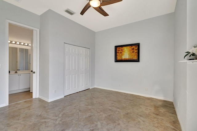 unfurnished bedroom featuring a closet, visible vents, light tile patterned flooring, ensuite bath, and baseboards