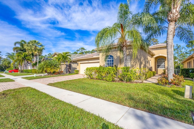 mediterranean / spanish-style home with a front yard, decorative driveway, an attached garage, and stucco siding