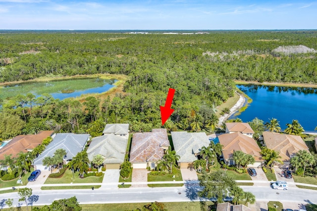 birds eye view of property featuring a water view, a wooded view, and a residential view