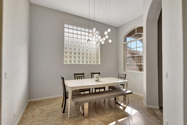 dining area featuring a notable chandelier, light tile patterned flooring, and baseboards