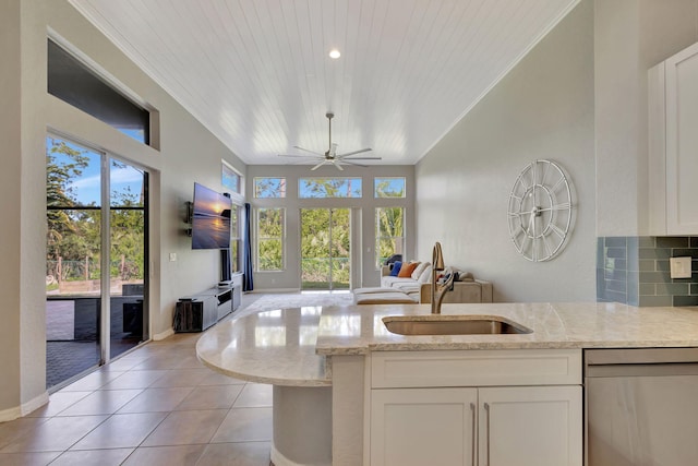 kitchen featuring a sink, white cabinets, open floor plan, light stone countertops, and dishwasher