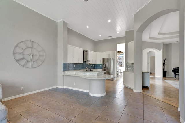 kitchen with light tile patterned floors, stainless steel fridge with ice dispenser, ornamental molding, a peninsula, and white cabinetry