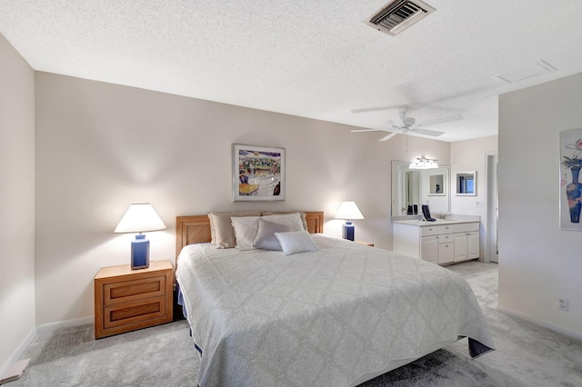 carpeted bedroom with ceiling fan, ensuite bathroom, and a textured ceiling