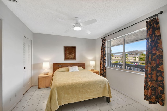 bedroom featuring light tile patterned flooring, ceiling fan, and a textured ceiling