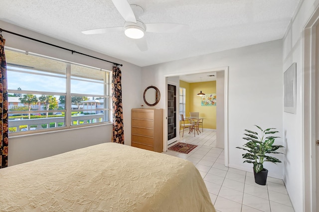 tiled bedroom featuring ceiling fan and a textured ceiling