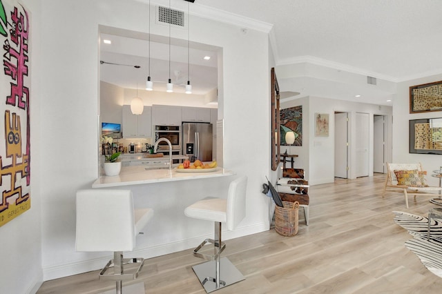 kitchen with pendant lighting, a breakfast bar, stainless steel refrigerator with ice dispenser, light hardwood / wood-style floors, and kitchen peninsula